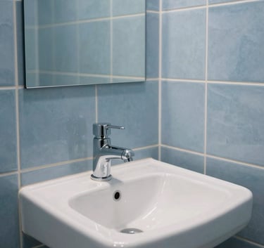 A pristine, modern bathroom with slate blue tiles showing a perfectly functioning sink and pipes, bright and clean photography.