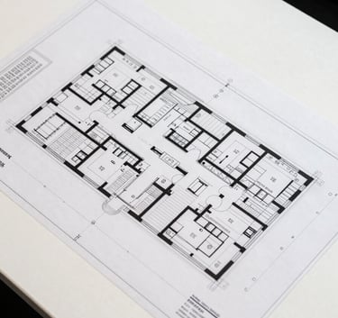 Top-down view of a professional architectural floor plan for a healthcare facility, featuring precise lines, room labeling, and a clean, modern drafting style on a white desk.
