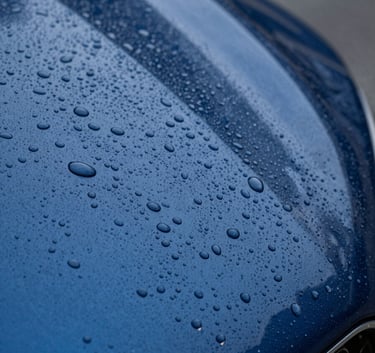 A macro shot of water droplets beading perfectly on a ceramic-coated car hood. The surface is a deep metallic blue resembling #003D5B. Professional studio lighting emphasizes the depth of the paint correction. The composition is focused on the texture and the hydrophobic effect of the premium coating.