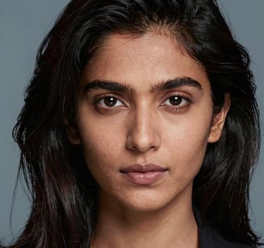 A professional portrait of a South Asian / Indian person with healthy, lustrous dark hair, styled to perfection. The backdrop is a soft blue-grey, conveying a sense of luxury and expert care in a high-end salon.