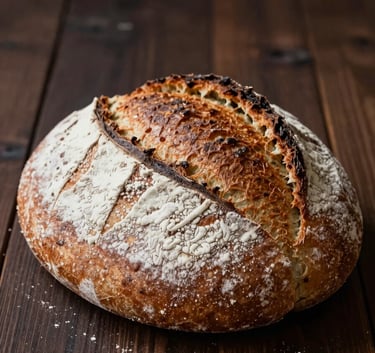Close-up of a rustic loaf of bread with a scored crust, dusted with off-white flour, sitting on a dark chocolate brown wooden table, warm and inviting atmosphere.