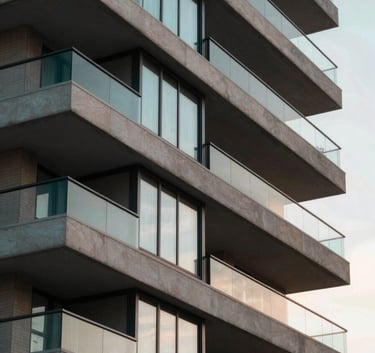 Modern architectural detail of a high-end Brazilian apartment building balcony, clean lines, sunset lighting reflecting on glass, sophisticated real estate photography with deep teal and beige tones.
