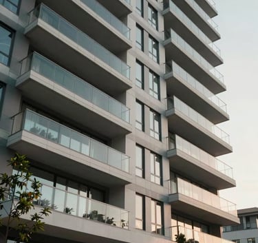 A sharp, low-angle photograph of a modern, multi-story apartment building in North America / US with clean lines, glass balconies, and professional landscaping.
