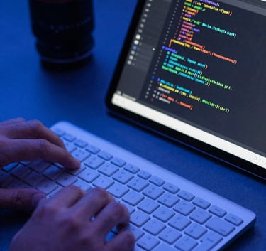 Close-up of a keyboard and a modern tablet displaying software code, held by a professional in a South American / Venezuelan workspace, sleek lighting in shades of Royal Blue.