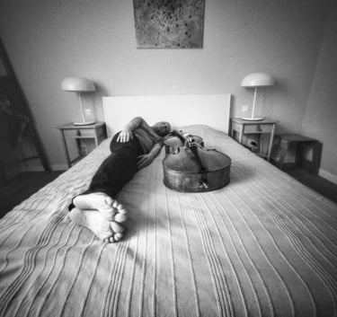 Musician relaxing on bed with cello