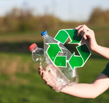 A person holding plastic water bottles and a green recycling symbol outdoors to promote sustainability.