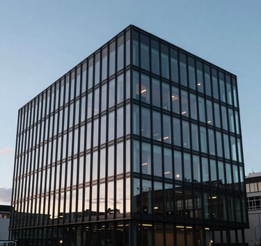 The sleek glass exterior of a modern British office building in Bristol, reflecting a soft light blue sky at dusk, conveying professional stability.