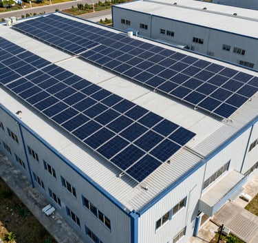 Professional aerial view of an industrial solar panel installation on a factory roof, featuring clean lines and modern design in a North American / Industrial context.