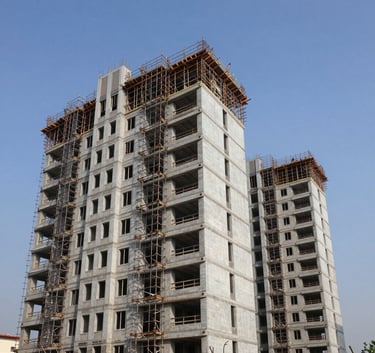 A wide-angle professional photograph of a modern residential development in India under construction, featuring complex scaffolding and clean structural lines against a clear blue sky.