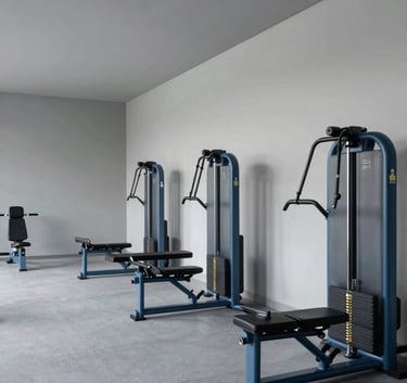 A minimalist, modern high-performance training center with pale grey walls and slate blue equipment, wide-angle interior photography.