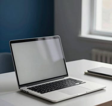 Professional photography of a minimalist workspace in a North American / US creative studio. A sleek aluminum laptop sits on a light desk, with subtle accents of Deep Midnight Blue in the background decor. Soft morning light streams through a window, creating a sophisticated and innovative mood.
