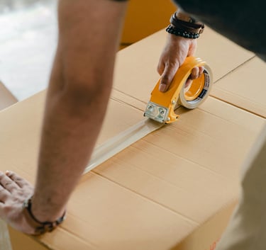 person putting tape on a moving box