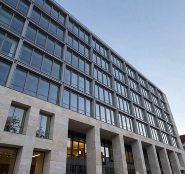 Photography of a grand, modern European university building facade in Brussels with sleek glass and steel. Low-angle shot during blue hour with off-white stone.