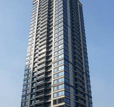 Architectural photography of a modern high-rise luxury condominium reflecting the blue sky in a North American downtown district, sophisticated navy and light gray facade.