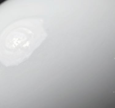 Close-up macro shot of a flawlessly smooth and glossy white ceramic surface with clean reflections, bright studio lighting, emphasizing the premium quality of the finish.