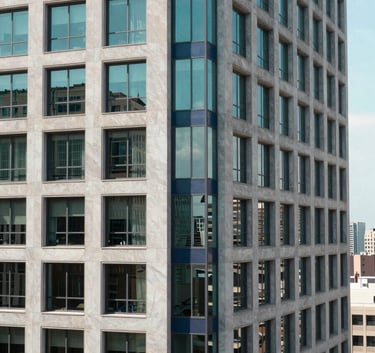 Modern high-rise office building window with a view of a clean North American cityscape at noon, turquoise and navy blue accents in the decor.