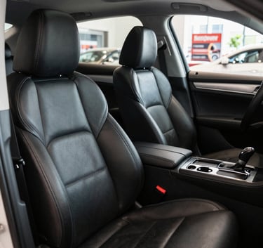 A wide-angle photography shot of a meticulously clean car interior, focus on the leather seats and polished dashboard, bright daylight through the window, North American detailing shop background.