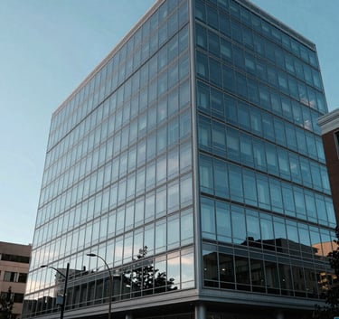 A wide angle photograph of a modern glass office building in Spokane, Washington, reflecting the clear blue sky, representing corporate stability and growth.