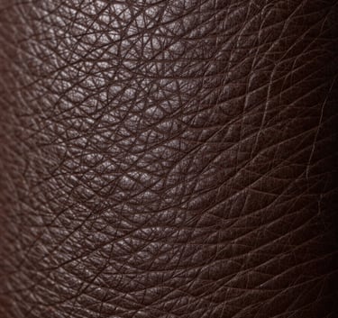 Extreme close-up of premium dark chocolate brown leather grain, showing sophisticated texture and high-quality craftsmanship, professional lighting.