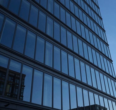 A low-angle shot of a modern architectural glass facade in a Central European city, reflecting a deep midnight blue sky, clean and professional photography.