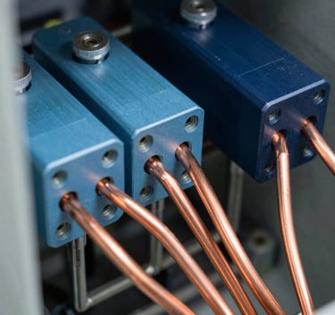 A close-up, high-detail photograph of professional electrical components and copper busbars inside a high-quality control panel. The lighting is crisp and clean, highlighting the steel blue and dark navy metallic surfaces, emphasizing precision engineering.