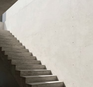 Faint, high-key architectural photography of a concrete stairwell with sharp geometric shadows, very low opacity against an off-white background, reflecting international studio-grade aesthetics.