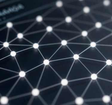 Abstract close-up of a digital glass screen with glowing network nodes and data connections in #A0A0A0 silver against a deep #1A1A1A background, representing innovation and intelligence.