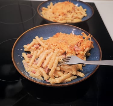 Gratin de macaronis dorés à l'emmental et lardons, nappe de sauce onctueuse au comté dans un plat