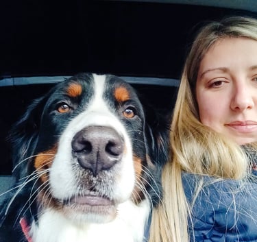 a woman in a blue jacket and a dog in a car