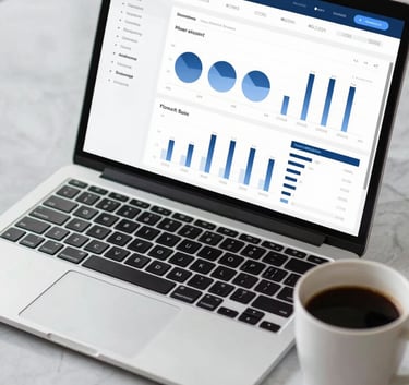 Close up of a modern laptop and business coffee cup on a light gray marble desk, displaying a clean financial dashboard with professional UI in #0A244A and #3F5B75 tones.