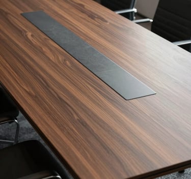 A high-angle professional photograph of a minimalist mahogany and slate-grey conference table in a North American / US executive suite, flooded with soft natural light.