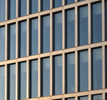 A minimalist and modern architectural detail of a high-end commercial building facade in Portugal, featuring clean lines, glass, and steel, reflecting a clear blue sky, photography with golden hour light.