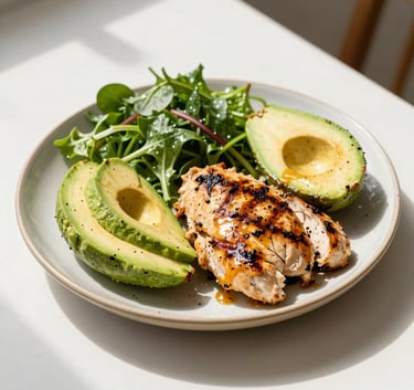 A close-up, high-quality photograph of a vibrant, healthy meal with grilled chicken, avocado, and leafy greens on a ceramic plate, placed on a clean white table in a sunlit North American home. The image conveys health, balance, and the nutritional aspect of fitness coaching.