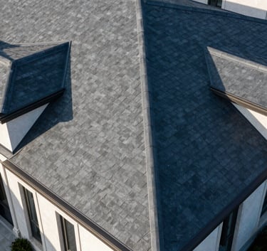 A professional aerial photograph of a luxury residential home with a perfectly installed dark slate roof, bright morning sunlight creating sharp shadows, high contrast and clean aesthetic.