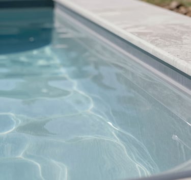 A close-up of a high-quality fiberglass pool shell being professionally installed in a residential Idaho setting. The surface is shimmering and smooth, reflecting the light grey-blue palette (#C4D1D1). The image feels clean, approachable, and highly professional.