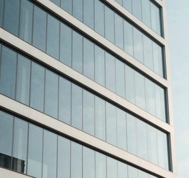 A sleek, minimalist photography of a modern Italian business building glass facade, reflecting a clear sky, symbolizing transparency and efficiency, white and pale blue tones.