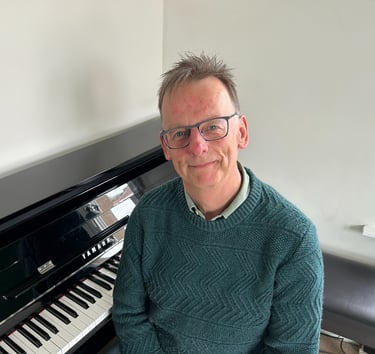 Photo of Steven with a piano behind him