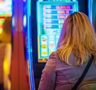 A blonde woman plays a glowing slot machine in a brightly lit Las Vegas casino.