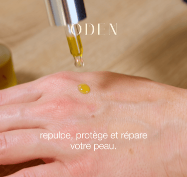 a person's hand holding a bottle of oil cosmetic