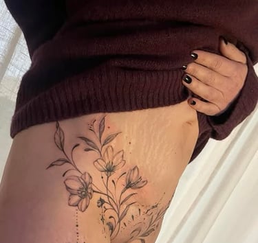 Une femme avec un tatouage sur sa cuisse sur cicatrice abdominoplastie montrant le côté de sa cuisse