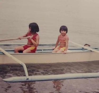 My sister and I on a tropical boat in the water as children.