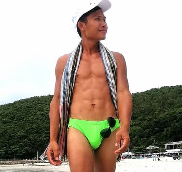 Man walking along Pattaya Beach wearing green swimming trunks.