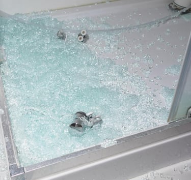 Shattered shower glass on a shower base showing need for urgent shower glass replacement in Auckland