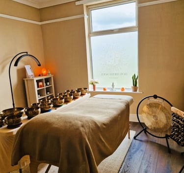 Treatment couch with singing bowls laid on a table, gong and seed chimes