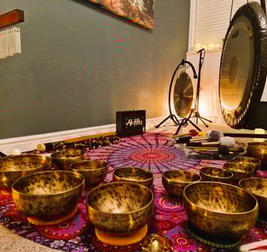 Shruti box, chimes, gongs, and many singing bowls arranged on a mat