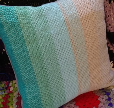 a tunisian crochet pillow with a colorful blanket