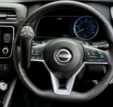 A Nissan steering wheel featuring an attached handicap driving aid hand control for accessible vehicle operation.