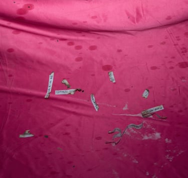 Handwritten paper slips scattered on a stained pink fabric surface for ritual or spell work.