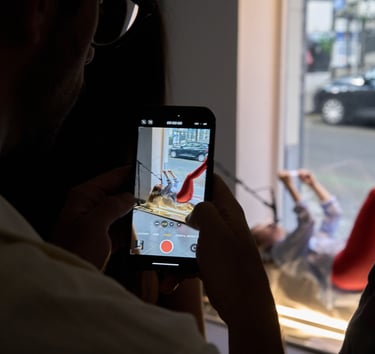 A person recording a smartphone video of a creative studio photoshoot with a model.