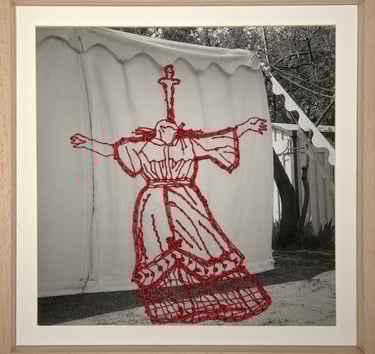 Framed black and white photo featuring red embroidery of a woman's dress onto a canvas tent.